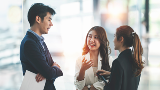 Three individuals in an office setting talking to each other