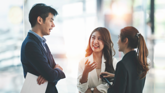 Three individuals in an office setting talking to each other