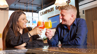 Two individuals smiling while enjoying a toast with drinks in their hands