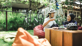 Two individuals enjoying tea outside with Bicycles behind them 
