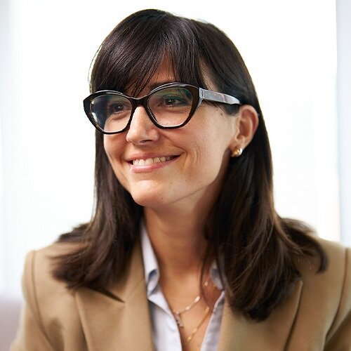Smiling woman in glasses and tan blazer