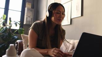 Individual with headphones on while using a laptop