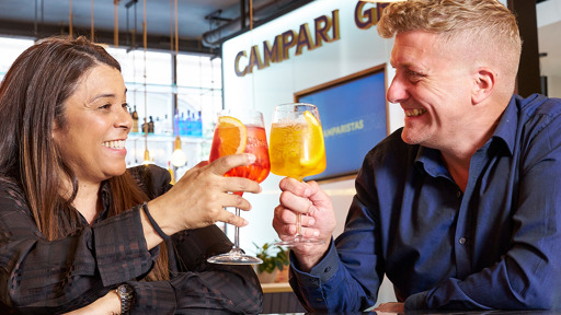 Two individuals smiling while enjoying a toast with drinks in their hands