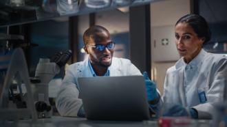 two biotech researchers discussing what is on a laptop screen