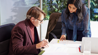 Two people analyzing documents at a desk