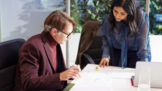 Two people analyzing documents at a desk