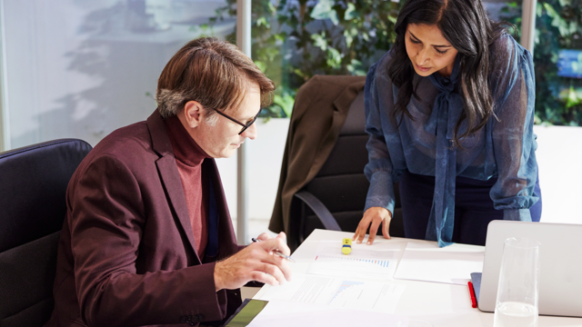 Two people analyzing documents at a desk